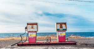 Vintage gas pumps on a deserted seashore with a clear sky and ocean view.