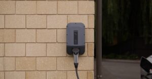 A wall-mounted electric vehicle charging station installed on a brick wall in Christchurch, New Zealand.